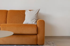 Un canapé avec un coussin et une petite table ronde placée devant.