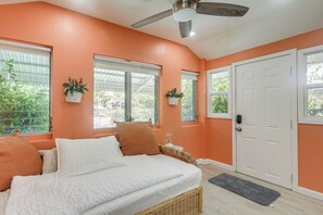 Un dormitorio con cama, ventanas, ventilador de techo y puerta.
