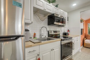 A modern kitchen with stainless steel appliances, white cabinetry, and a built-in oven. - Walk to Dtwn! Home 2 Mi to Lake Worth Beach Park (Lake Worth Beach)