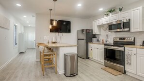 A modern kitchen with white cabinetry, stainless steel appliances, and a central island with seating. - Walk to Dtwn! Home 2 Mi to Lake Worth Beach Park (Lake Worth Beach)