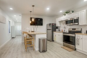 A modern kitchen with white cabinetry, stainless steel appliances, and a central island with seating. - Walk to Dtwn! Home 2 Mi to Lake Worth Beach Park (Lake Worth Beach)