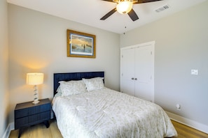A bedroom with a bed, a nightstand, a ceiling fan, a door, and a framed picture on the wall. - Waterfront Home w/ Deck & Views on Copano Bay! (Taft)