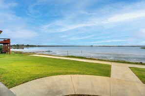 A waterfront property with a grassy lawn, a concrete pathway, and a wooden deck. - Waterfront Home w/ Deck & Views on Copano Bay! (Taft)