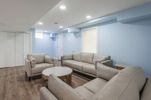 A room with beige leather sofas, a round coffee table, and a white door with an exit sign. - Family Home w/ Fenced Backyard, 16 Mi to DC! (Clinton)