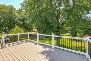 A wooden deck with a white railing, surrounded by lush green trees and a well-maintained lawn. - Family Home w/ Fenced Backyard, 16 Mi to DC! (Clinton)