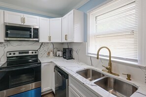 A kitchen with white cabinets, a stainless steel sink, a microwave, a stove, and a dishwasher. - Family Home w/ Fenced Backyard, 16 Mi to DC! (Clinton)