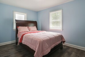 A bedroom with a bed, two windows with blinds, and a dark wooden floor. - Family Home w/ Fenced Backyard, 16 Mi to DC! (Clinton)