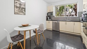 Et moderne køkken med spiseplads, med et rundt bord, to stole og en skål på bordet.