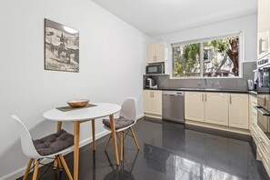 Eine moderne Küche mit Essbereich, mit einem runden Tisch, zwei Stühlen und einer Schüssel auf dem Tisch.