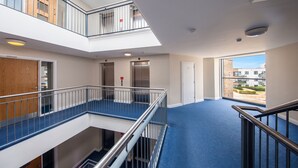 A multi-level interior with a central corridor, elevators, and a view of the outside.
