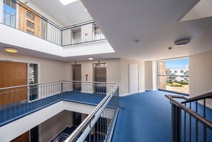 A multi-level interior with a central corridor, elevators, and a view of the outside.