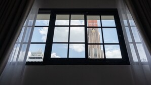 Una ventana con vistas a un edificio alto y una construcción más pequeña al fondo.