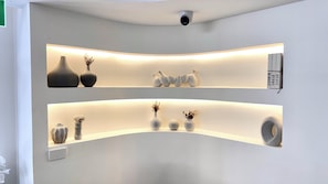 Un interior moderno con dos estantes iluminados que exhiben jarrones y objetos decorativos.