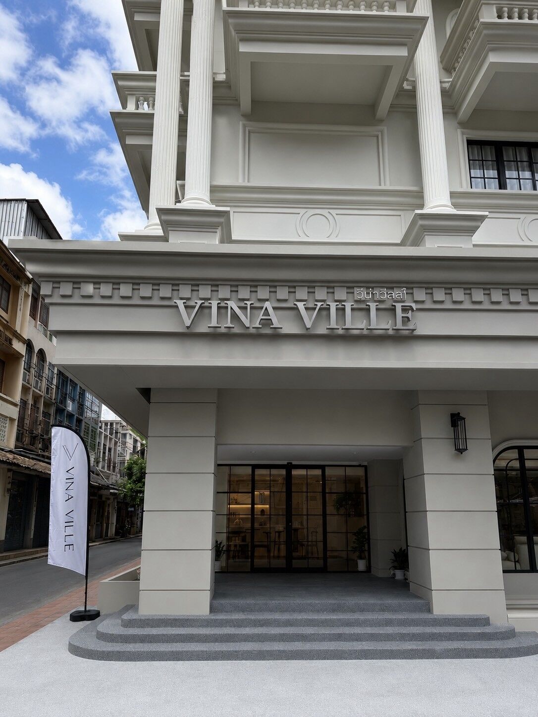 A entrada da Vina Ville, com uma fachada imponente, colunas grandes e um acesso destacado.