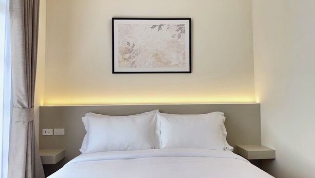 Una habitación de hotel con una cama, dos mesitas de noche, una lámpara de pared y una obra de arte abstracta enmarcada.