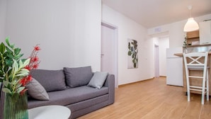A modern living room with a grey sofa, a white table, and a vase of red flowers.