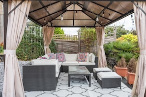 An outdoor patio with a covered seating area, including a sofa and two side tables. - Inviting 3BDR Garden Home in Sanderstead (Greater London)