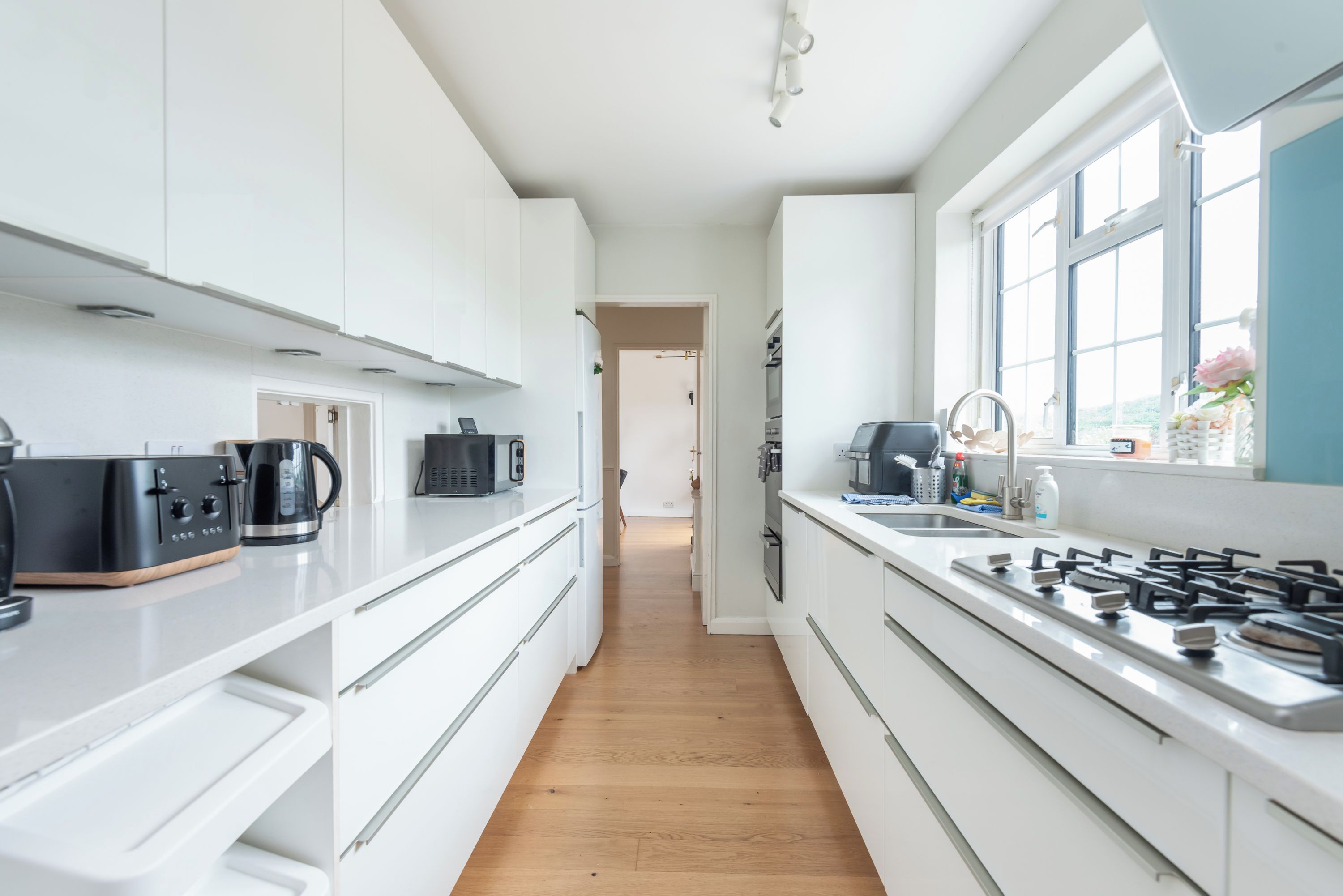 A modern kitchen with white cabinets, a stainless steel stove, and a window providing natural light.