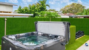 Ein Whirlpool mit Stufen, umgeben von einem gepflegten Rasen und einem Heckenstreifen.