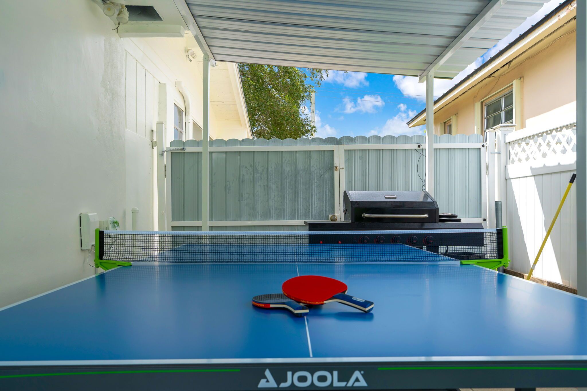 Une table de ping-pong avec un filet, une raquette rouge et une raquette bleue.