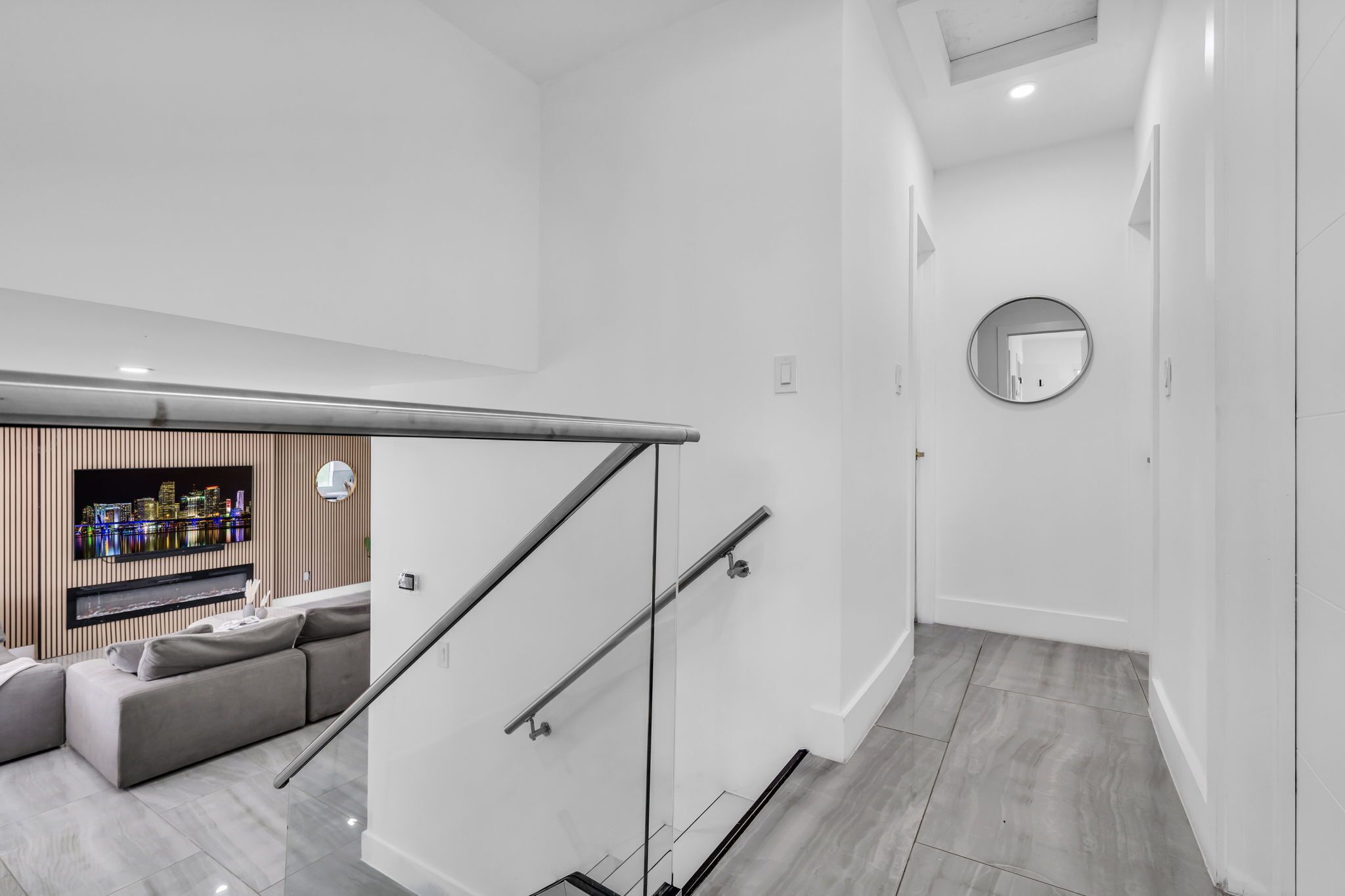 Een modern interieur met een trap, een zithoek met een bank en uitzicht op de stad.