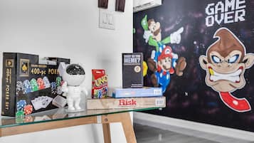 Een glazen displaytafel met verschillende gezelschapsspellen en een kunstwerk aan de muur.