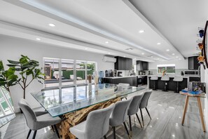 A modern kitchen with a glass dining table, grey chairs, and a view of the outdoors. - Miami Resort Villa with Jacuzzi & Sauna (Miami)