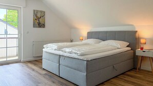A bedroom with a bed, a radiator, a painting, and a window. - Spacious, detached villa for 12 people near Winterberg (Grönebach)