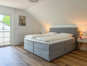 Ein Schlafzimmer mit einem Bett, einem Heizkörper, einem Gemälde und einem Fenster.