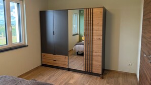 A bedroom with a wardrobe, a bed, and a window. - Newly Built Farmhouse-Style Vacation Rental Near the Borders of Luxembourg and Belgium (Üttfeld)