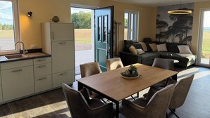 A modern kitchen with a dining area, a sofa, and a view of the outdoors. - Newly Built Farmhouse-Style Vacation Rental Near the Borders of Luxembourg and Belgium (Üttfeld)
