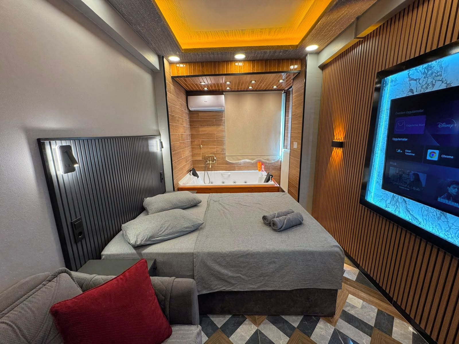 Una habitación de hotel moderna con cama, televisión, baño y zona de estar.
