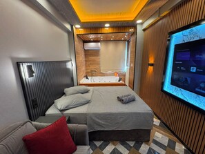 A modern hotel room with a bed, a TV, a bathroom, and a seating area. - ROYAL APART OTEL (Eskisehir)