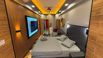 Habitación de hotel moderna con una cama, un televisor montado en la pared, un diseño de paneles de madera y un espejo.