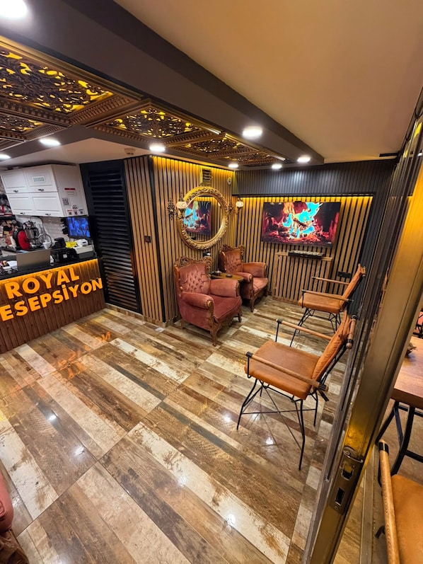 A room with a reception desk, plush seating, and a television screen.