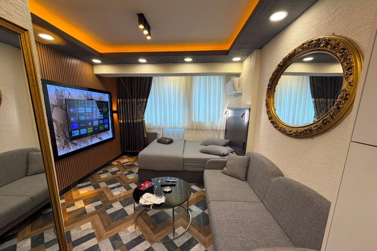 A modern living room with a flat-screen TV, a sofa, a coffee table, and a patterned floor.