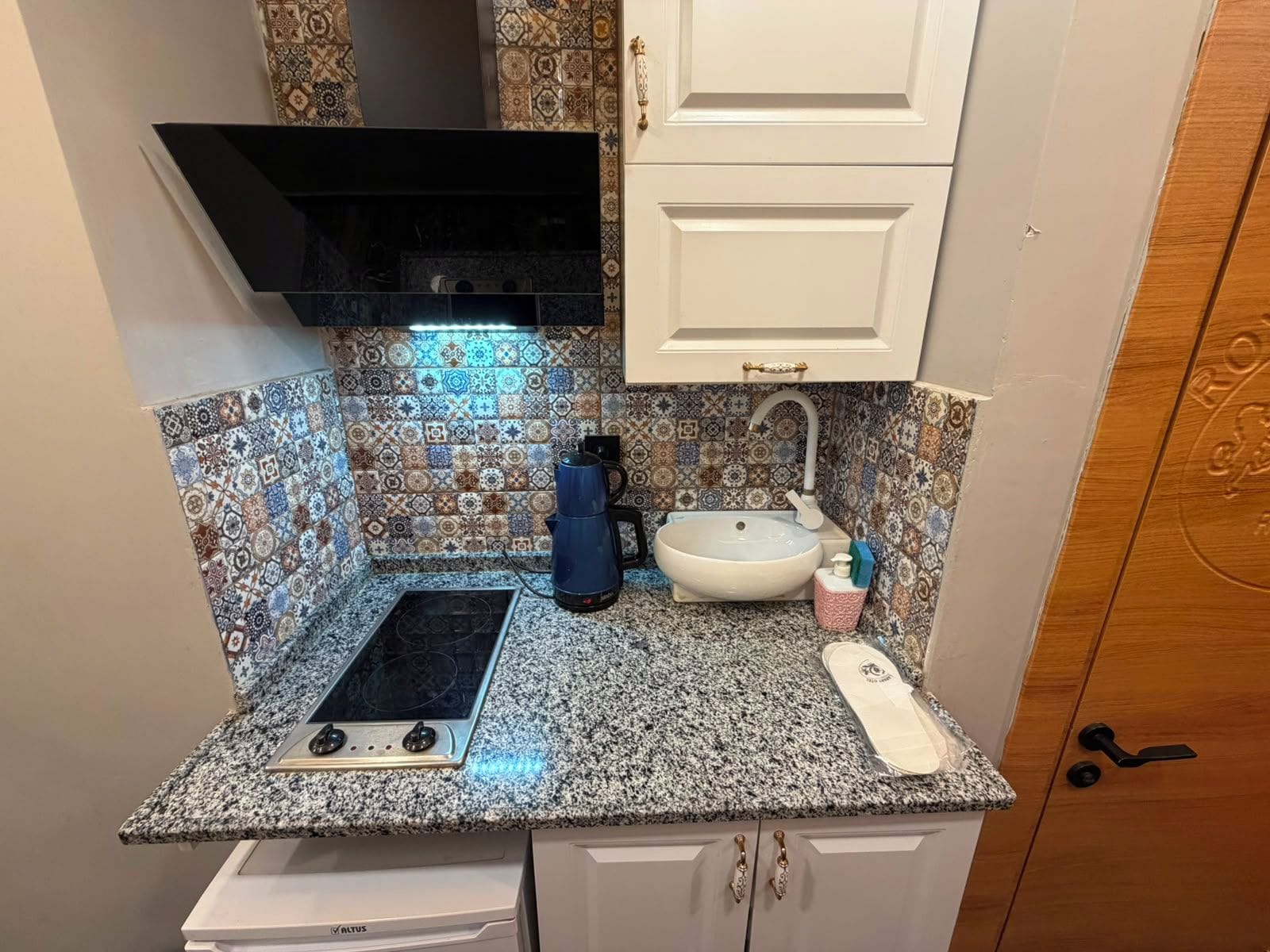 A compact kitchen with a gas stove, a sink, and a coffee maker.