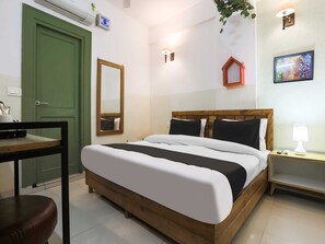 Ein Schlafzimmer mit einem Bett, einem Nachttisch, einer Lampe und einer grünen Tür.