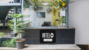 Ein Hotel-Rezeptionsbereich mit einer Rezeption, einem Schild mit der Auscheckzeit und einem Schild für das Hotel 'HOTEL O'.