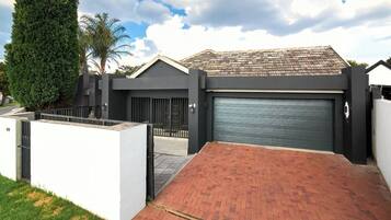 A modern house with a gated driveway, a garage, and a well-maintained lawn.