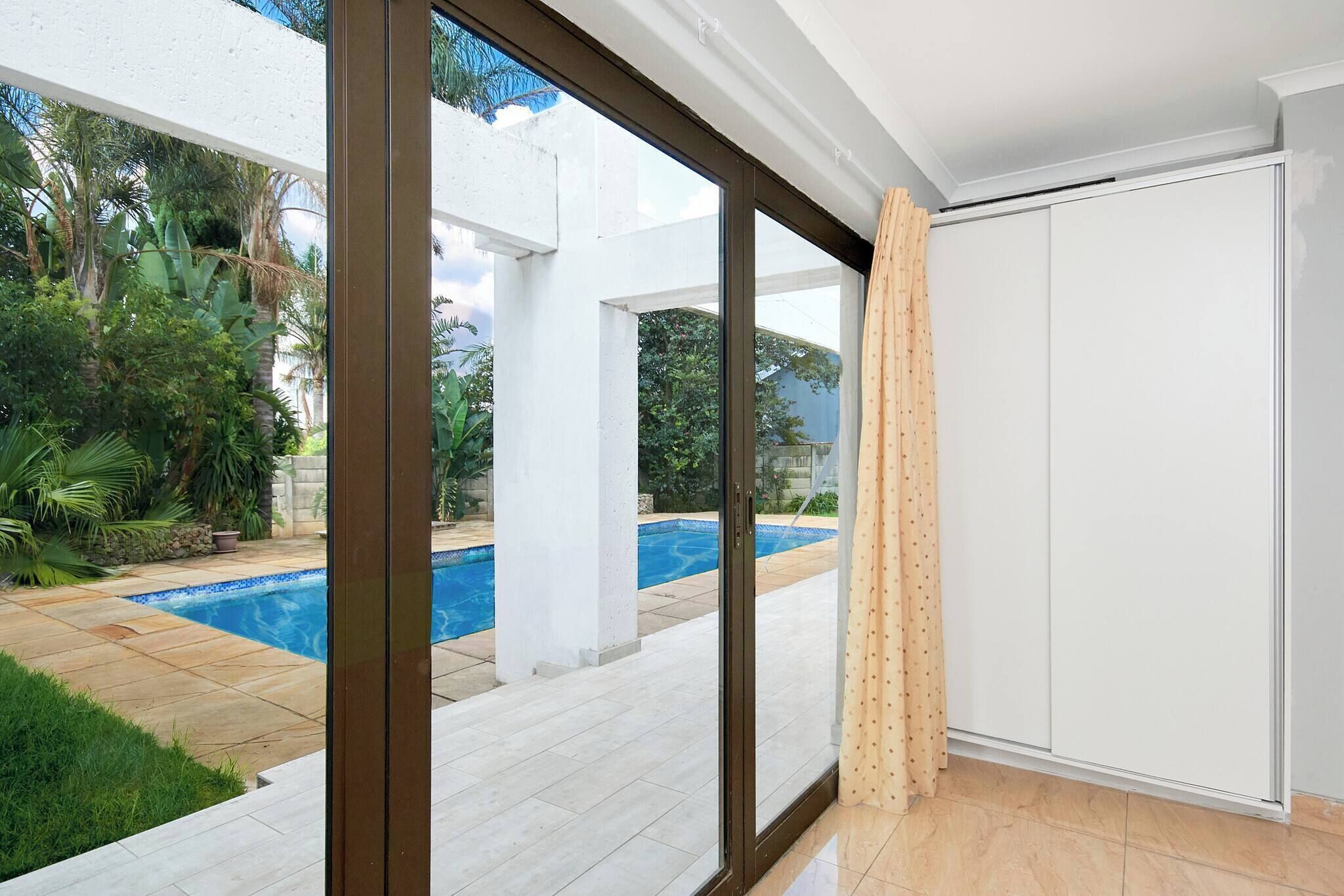 A room with a large sliding glass door leading to a pool area.