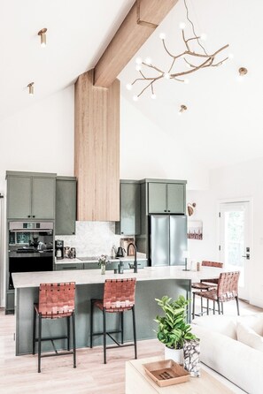 Una cocina moderna con una isla central, taburetes de bar y una lámpara colgante.