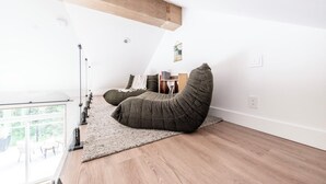 Ein schickes Schlafzimmer im Loft-Stil mit hohen Decken, einem großen Fenster und einer integrierten Bücherwand.