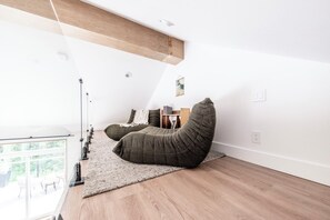 Ein schickes Schlafzimmer im Loft-Stil mit hohen Decken, einem großen Fenster und einer integrierten Bücherwand.