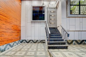 Una scala con ringhiera metallica che conduce a una porta, circondata da piastrelle decorate e un muro di legno.
