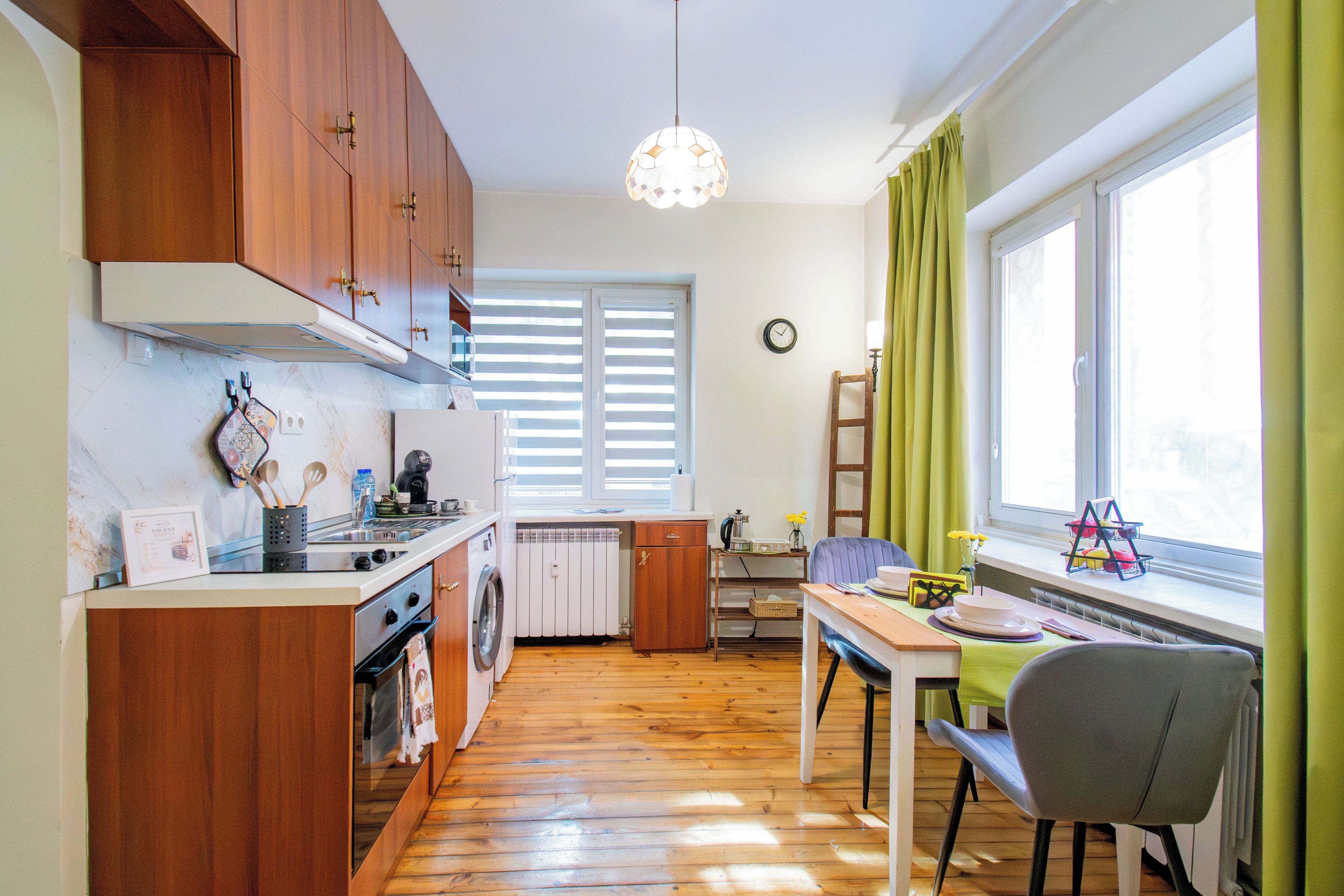 A compact kitchen with wooden cabinets, a built-in oven, and a dining area with a table and chairs.