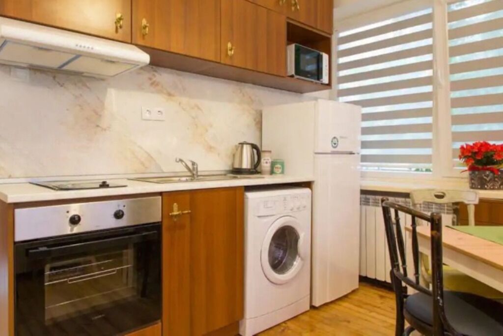 A compact kitchen with a built-in oven, a washing machine, and a microwave.
