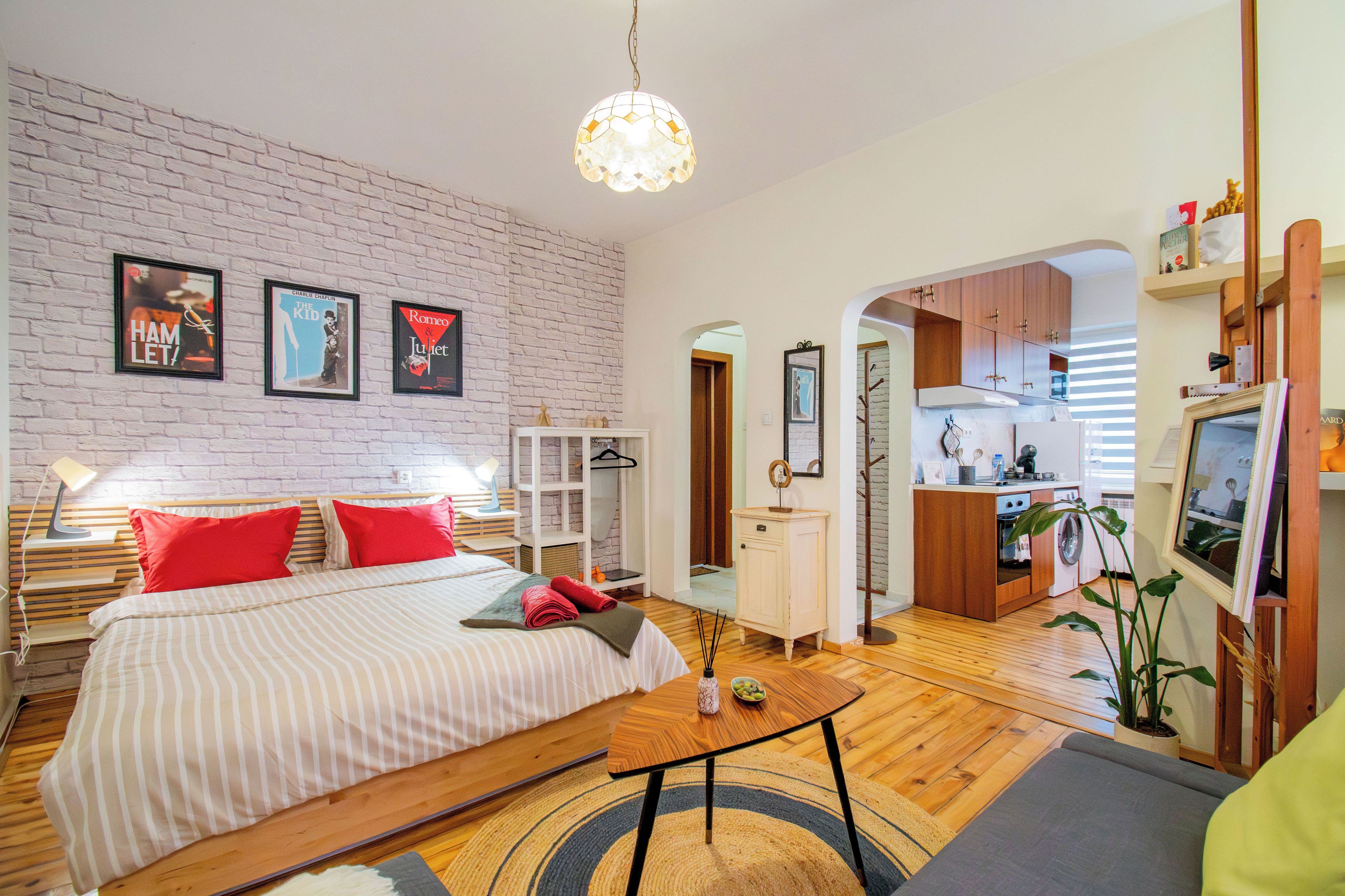 A bedroom with a bed, a bedside table, and a hanging light fixture.