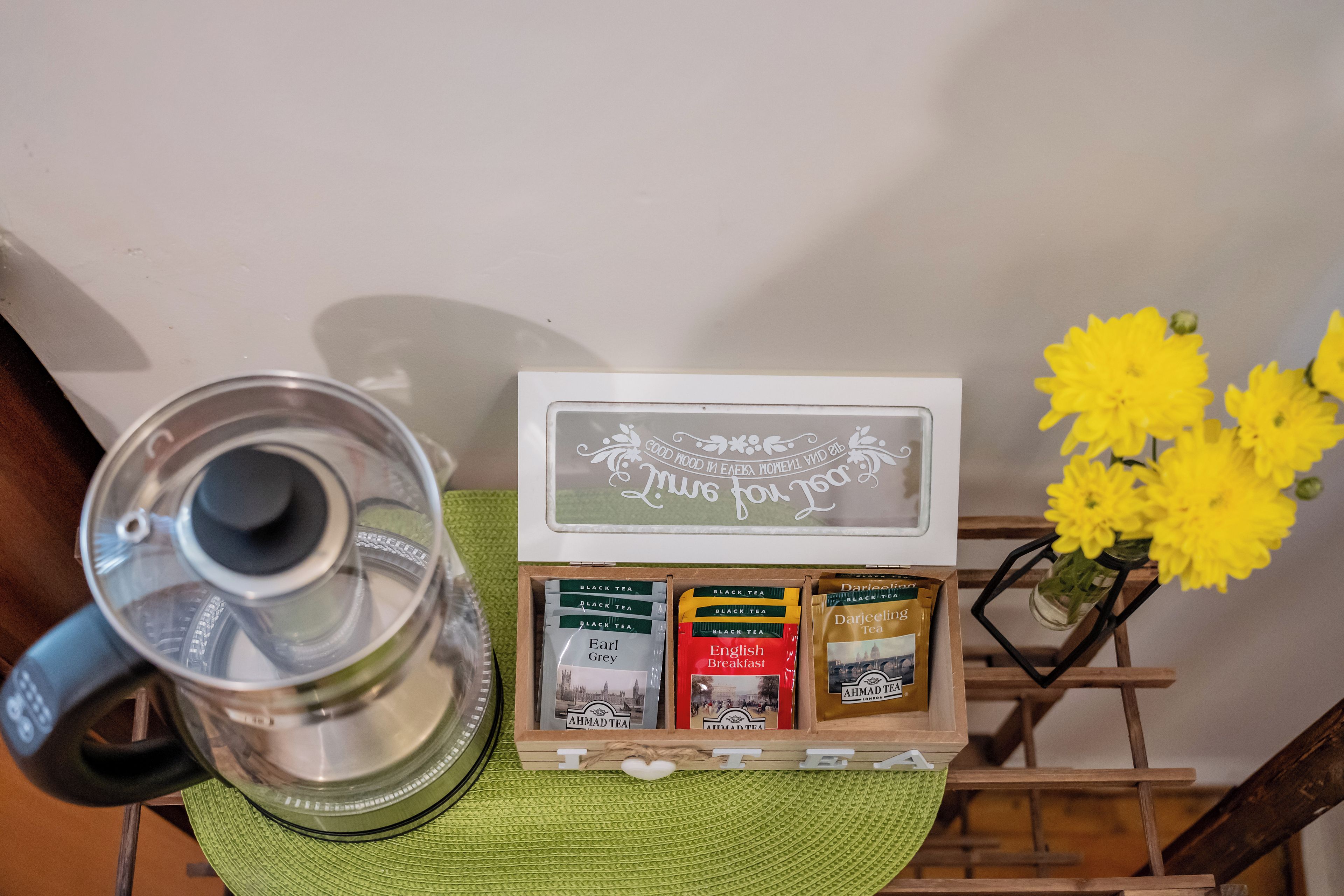 A coffee maker, a tea box with various tea brands, and a decorative sign with text.