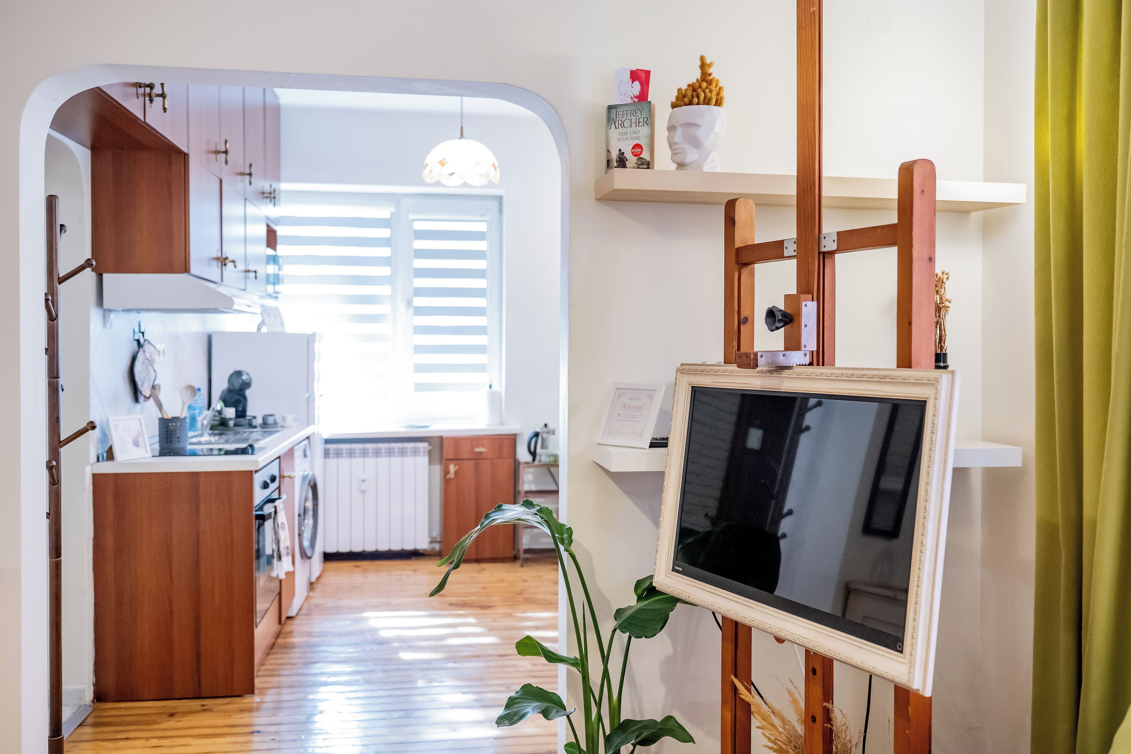A modern kitchen with wooden cabinets, a built-in oven, and a window with blinds.
